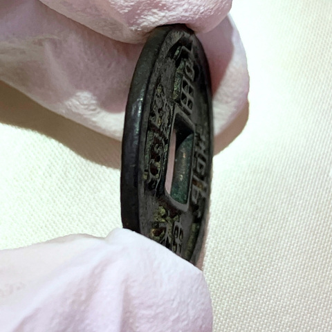 富壽神宝を側面から撮影した写真。鋳造された貨幣特有の厚みと、縁の形状が分かる。